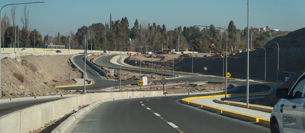Calzada nueva con columnas de alumbrado montadas, y una camioneta de Congenia en obra